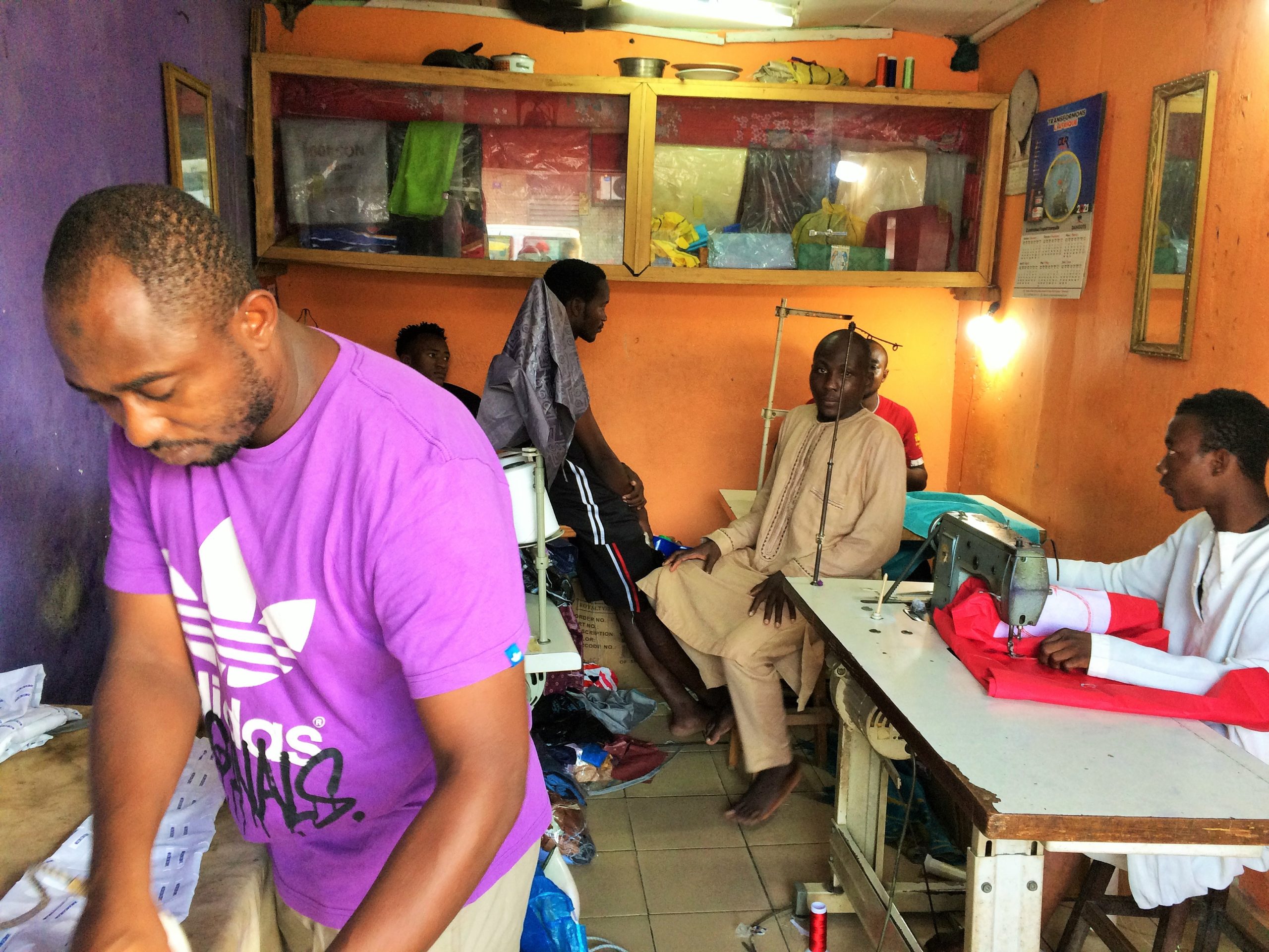 Abdoulaye-Mohamadou-tee-shirt-violetdans-son-atelier-de-couture-en-train-de-repasser-le-boubou-dun-client-a-quelques-jours-du-Ramadan-2021